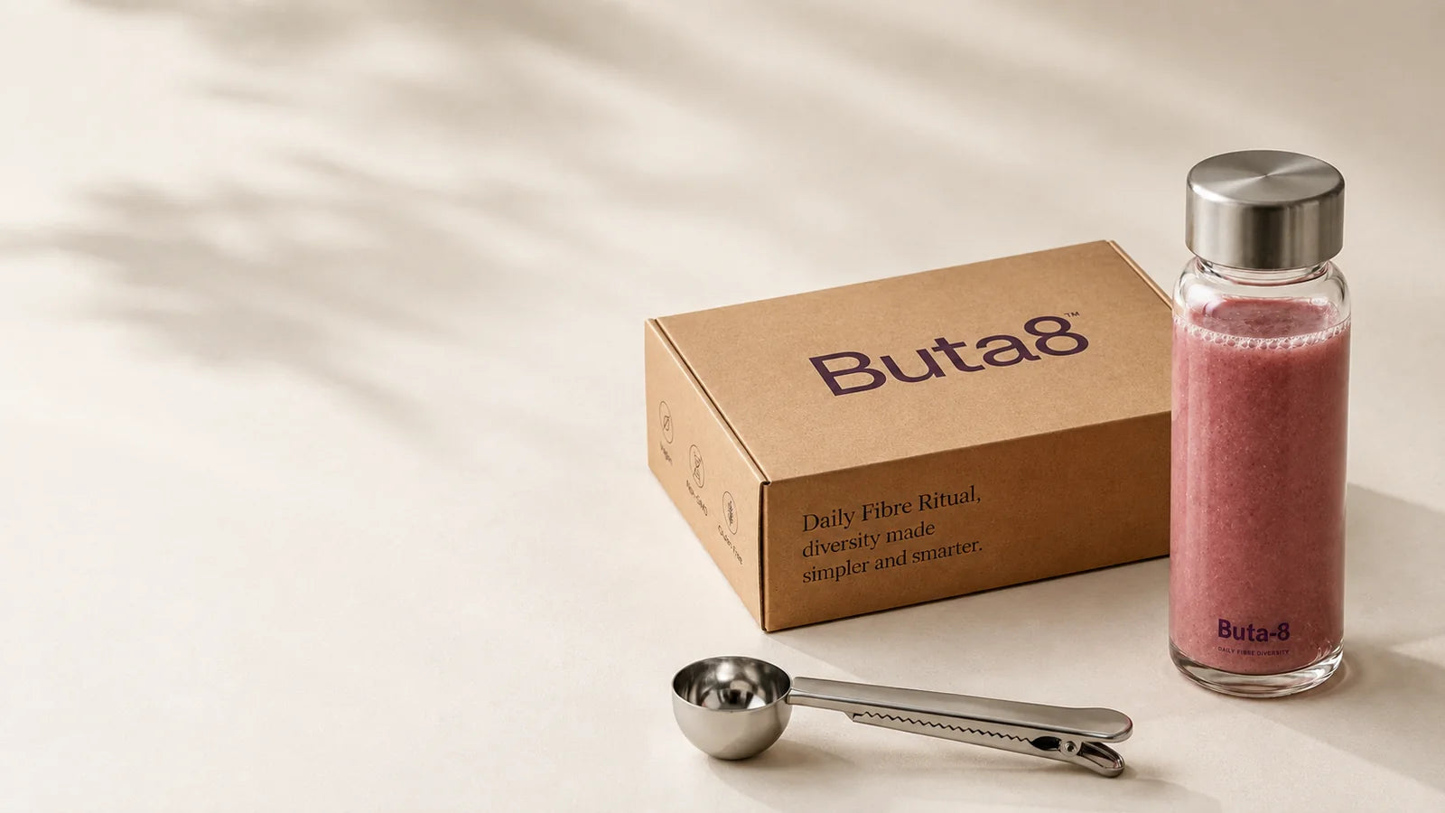 The Buta-8 box, a glass bottle of the prepared drink and the steel scoop, in morning light.
