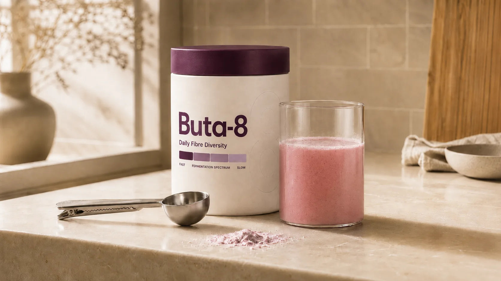 A Buta-8 tub, a measuring scoop and a glass of freshly mixed Buta-8 on a stone kitchen counter